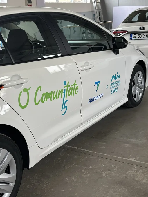 Inscripționare Autonom și Maratonul Internațional Sibiu pe ușile unui autoturism alb